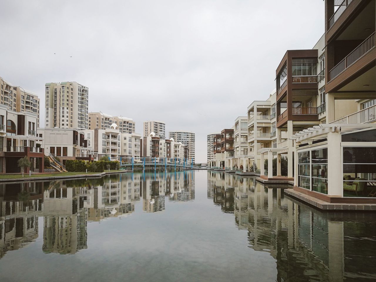 services-02 Modern residential buildings reflecting in a tranquil urban canal.