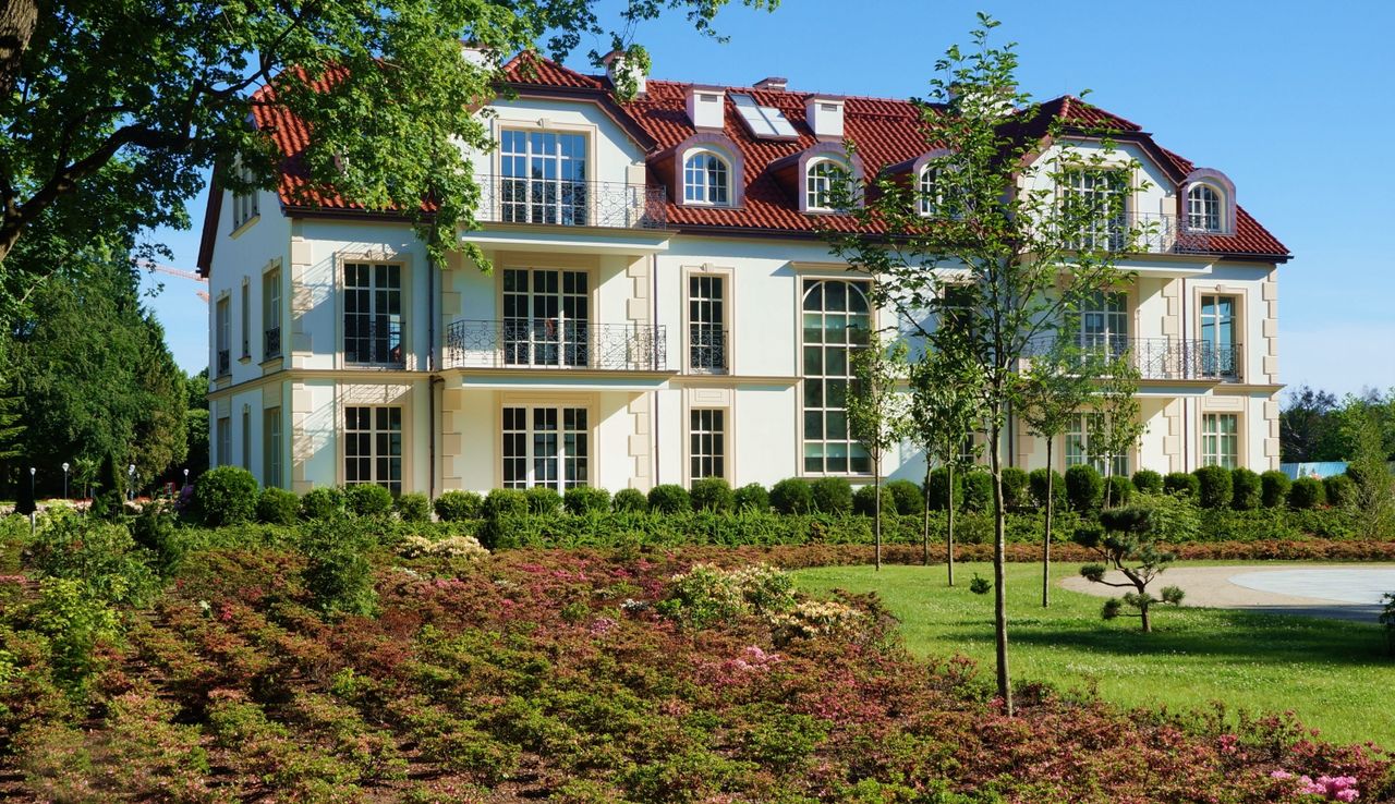 why-choose-us Sunlit residential building with lush garden in Gdansk Oliwa, Poland.