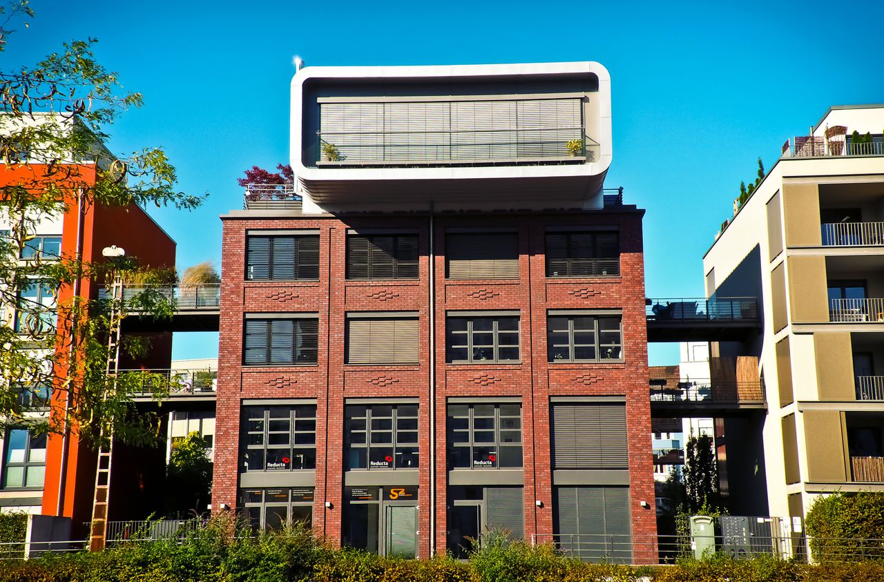 services-01 Contemporary brick apartment building with unique geometric shapes under a clear blue sky.