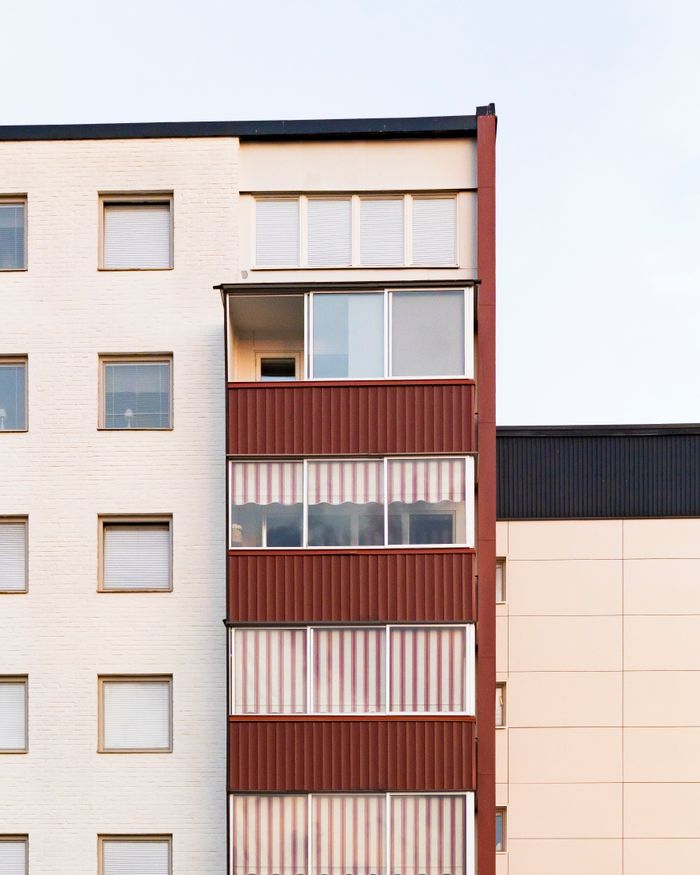 services-02 Capture of a modern residential building showcasing distinct red balconies against a neutral facade.