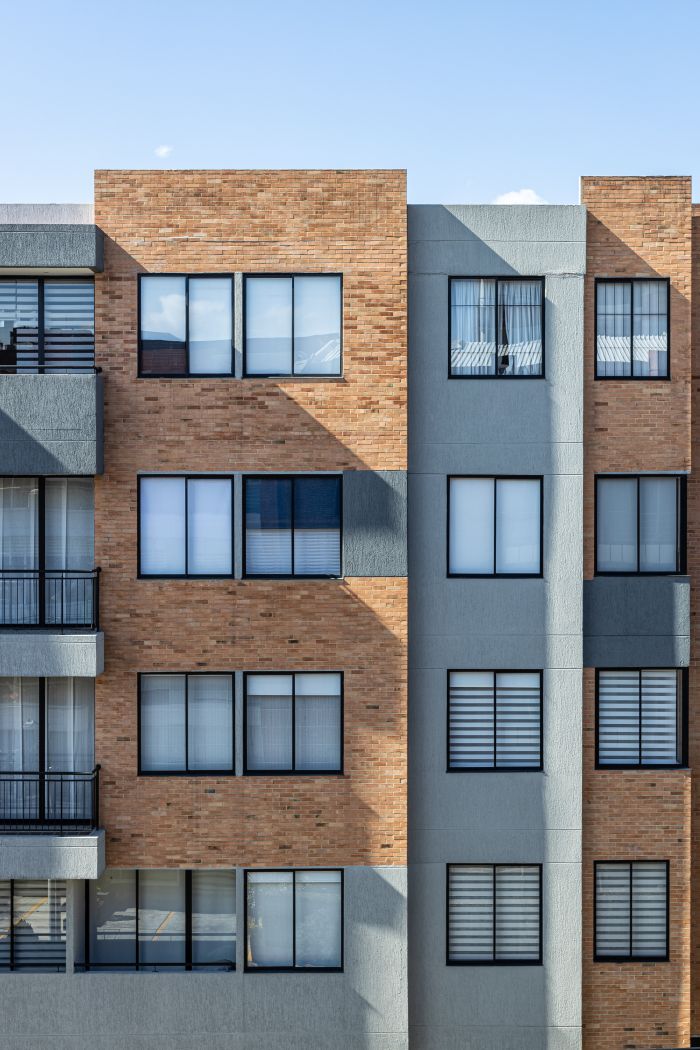 journey A modern apartment building showcasing a mix of brick and concrete elements under clear skies.